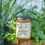 Jarmino Gemüsebrühe 350ml – Glasflasche auf natürlichem Untergrund, frische Kräuter im Hintergrund